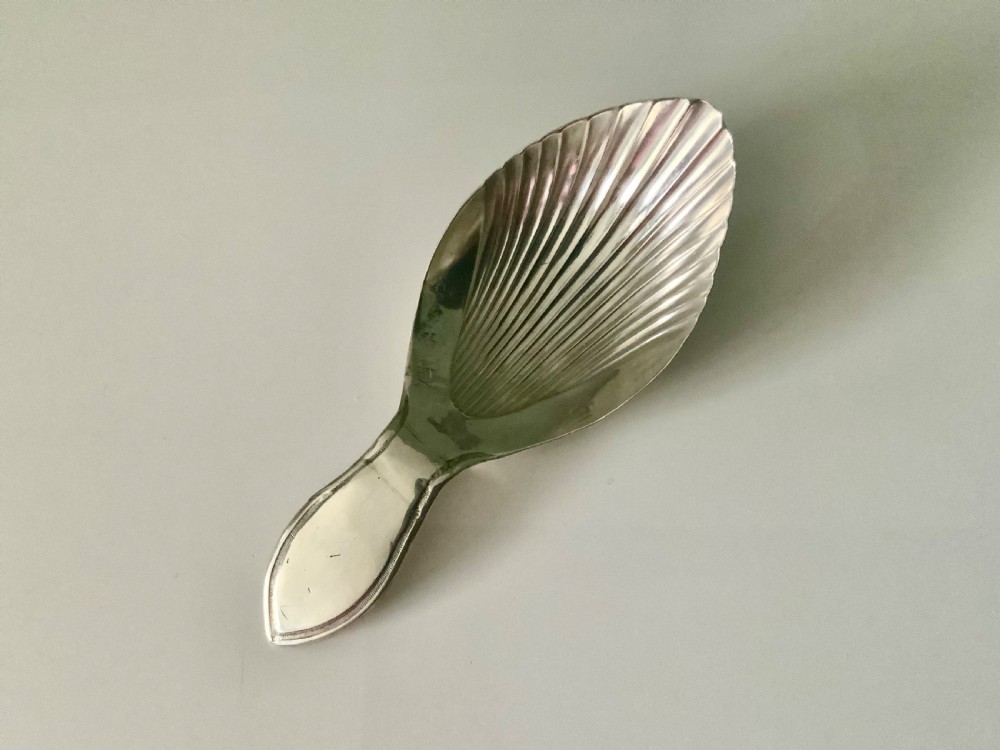 A Georgian sterling silver caddy spoon featuring a fluted shell bowl and a hallmarked handle. View II