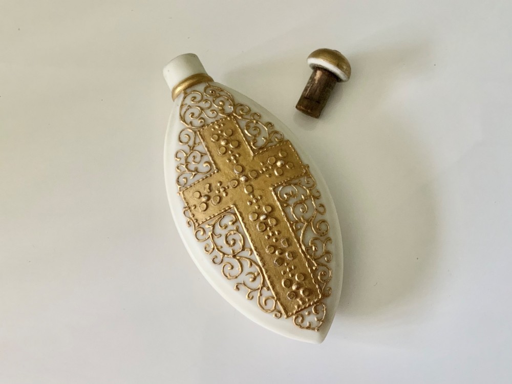 An elongated white parian ware scent bottle featuring raised gilded scrollwork and a central cross design. View IV