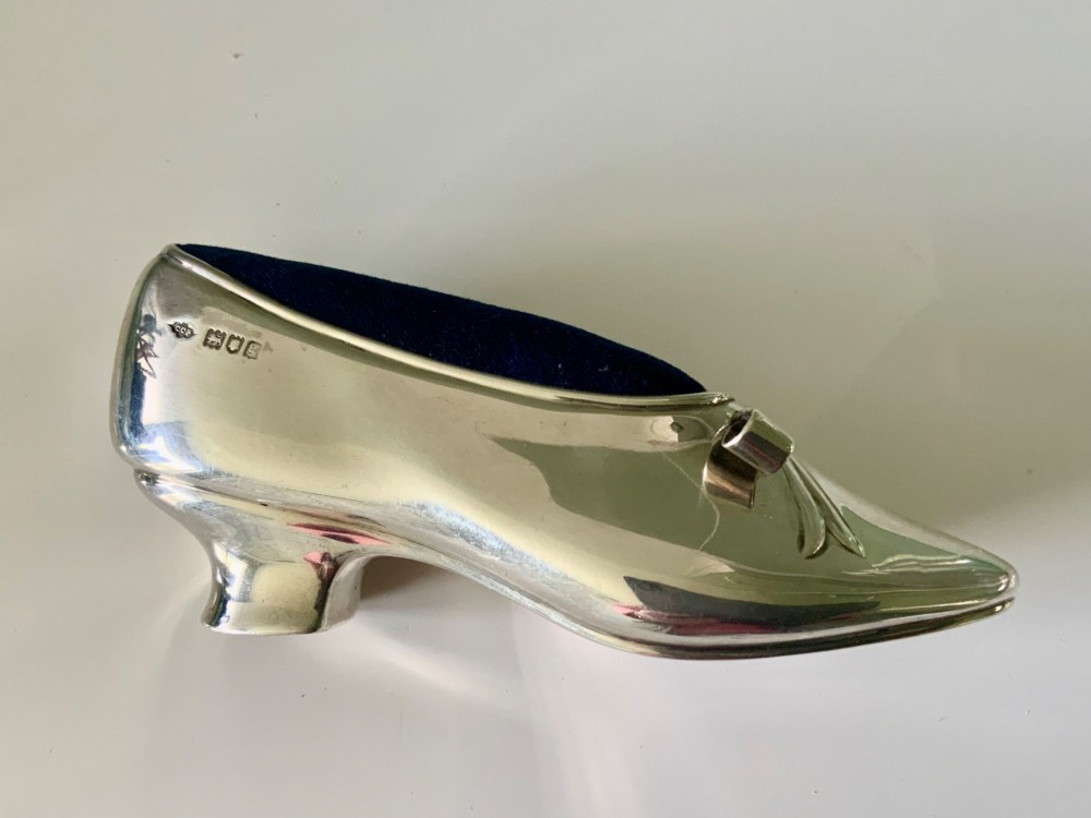 A silver novelty pin cushion shaped like a pointed shoe featuring a silver bow motif on the vamp and a navy blue velvet interior insert. View III