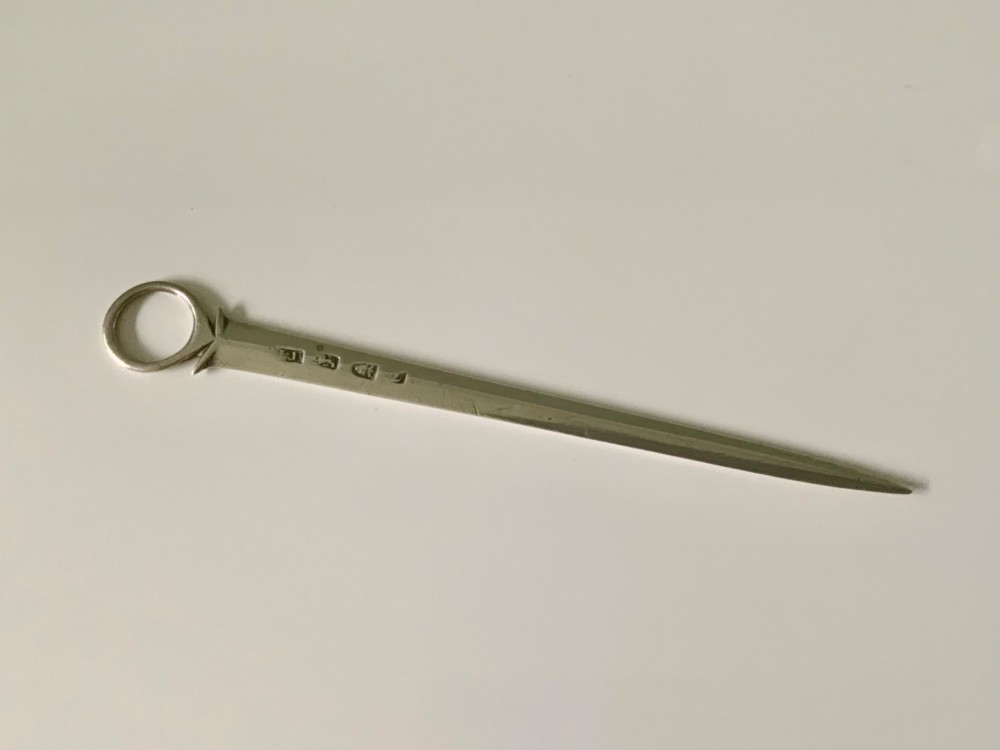 A Georgian sterling silver skewer featuring a flat tapered blade, stamped British hallmarks, and a circular ring finial.
