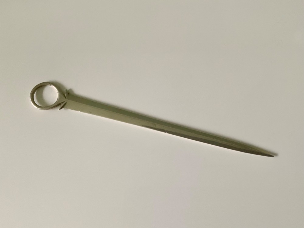 A Georgian sterling silver skewer featuring a flat tapered blade, stamped British hallmarks, and a circular ring finial. View II