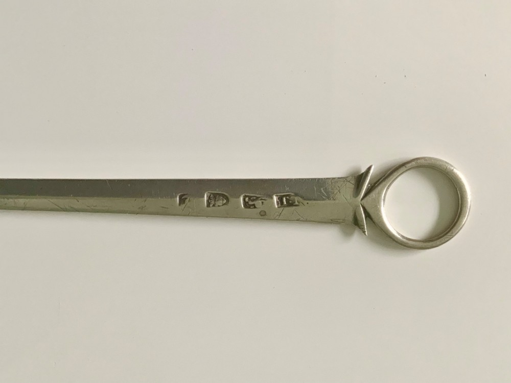 A Georgian sterling silver skewer featuring a flat tapered blade, stamped British hallmarks, and a circular ring finial. View III