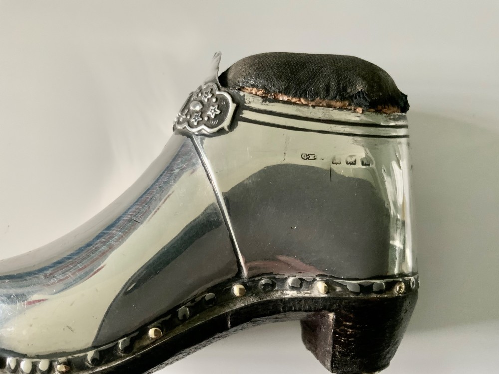 An antique sterling silver pin cushion crafted in the shape of a clog shoe with a dark velvet pad and visible hallmarks. View IV