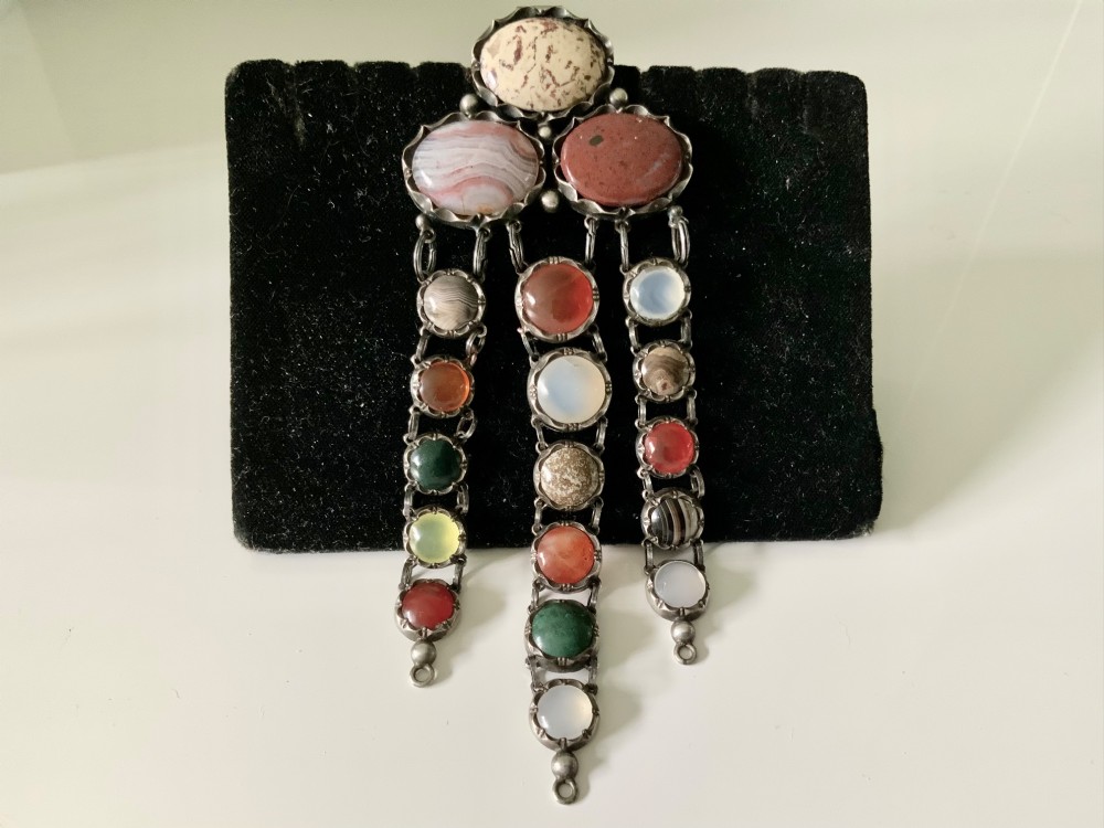 A Victorian silver chatelaine clip set with polished oval and circular multicolour agates and jaspers arranged in three articulated drops.