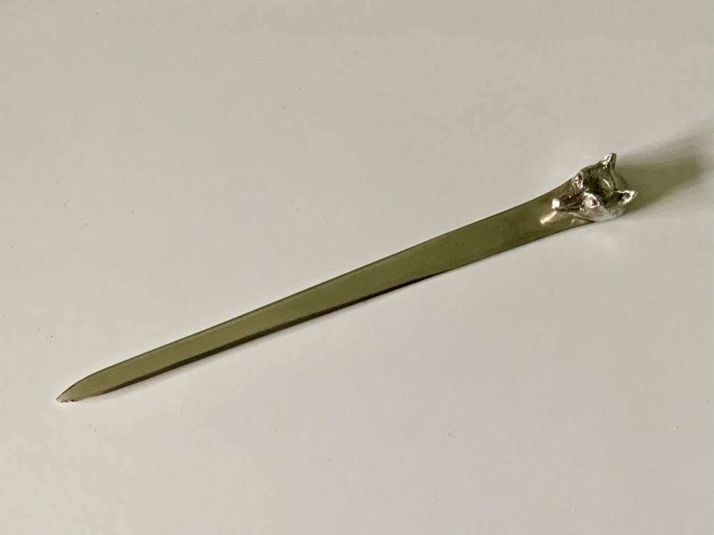 An antique sterling silver letter opener featuring a flat tapered blade and a detailed cast fox head terminal.