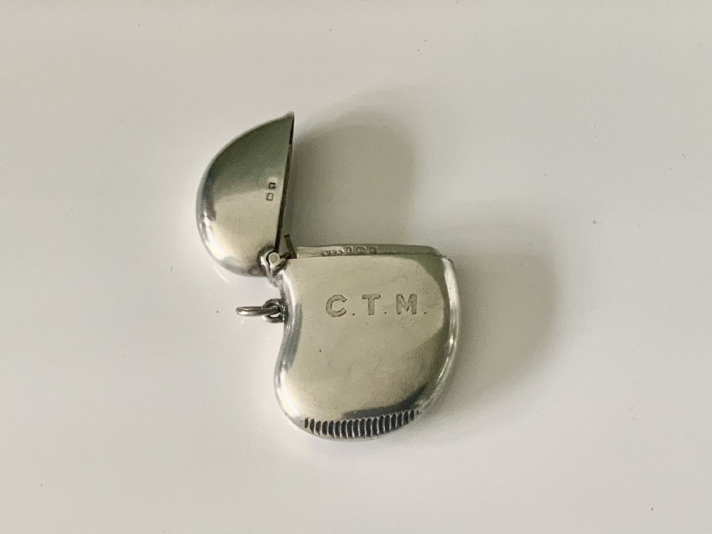 A kidney-shaped sterling silver vesta case featuring engraved monogram initials, a side suspension loop, and a serrated striking strip on the bottom edge. View III