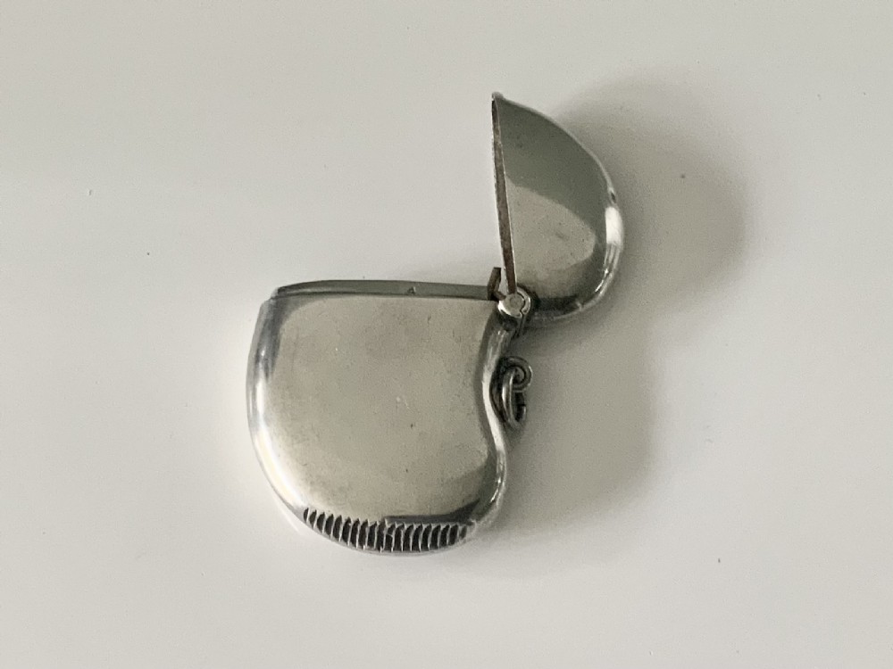 A kidney-shaped sterling silver vesta case featuring engraved monogram initials, a side suspension loop, and a serrated striking strip on the bottom edge. View IV