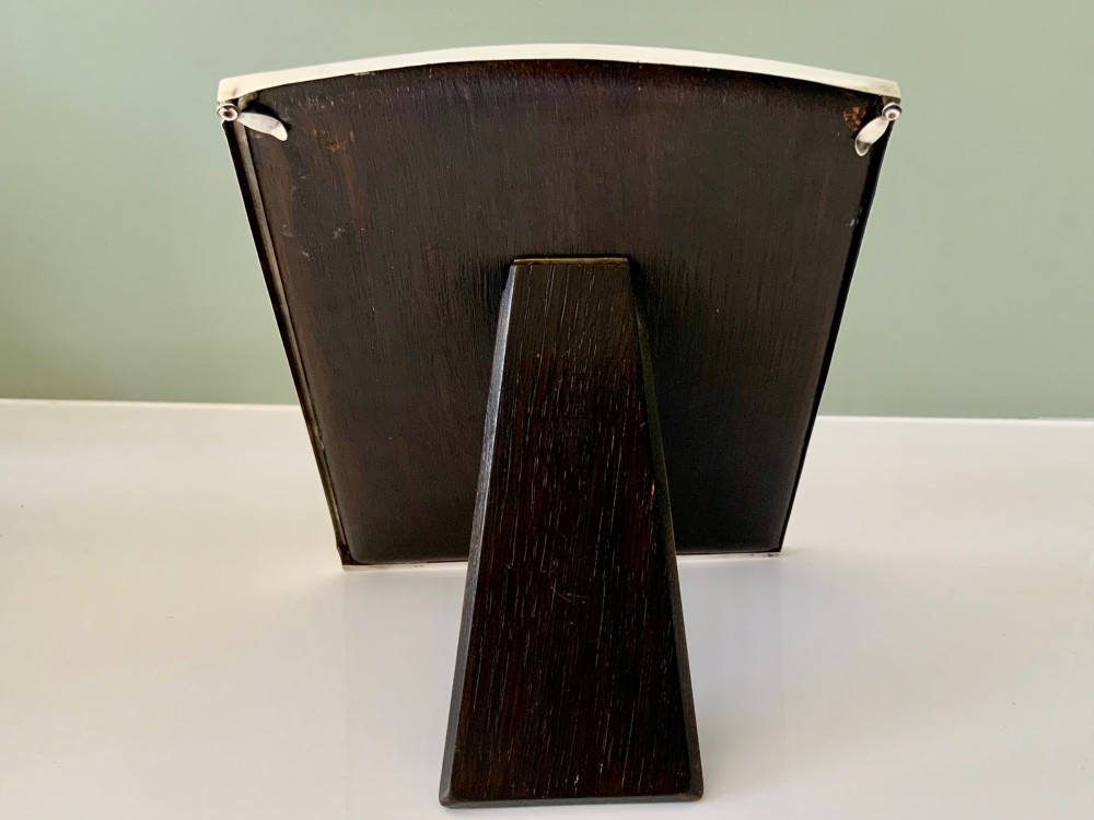 An Art Deco silver photo frame with a textured engine-turned border, an arched top profile, and a dark wooden interior backing. View III