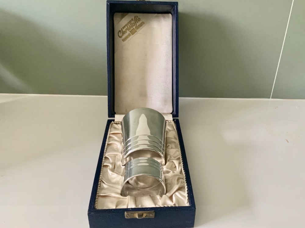 A silver-plated beaker and matching napkin ring with horizontal ridge details sit inside a blue presentation box lined with cream satin.