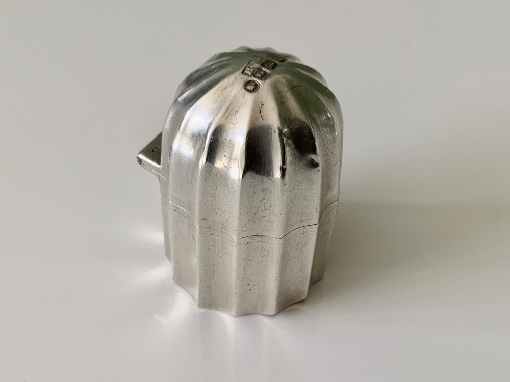 A small fluted sterling silver vinaigrette box featuring official hallmarks stamped onto its curved top section.