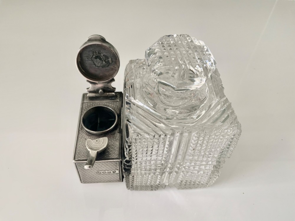 A square geometric cut glass travelling inkwell with a hallmarked sterling silver hinged lockdown mechanism attached alongside. View II
