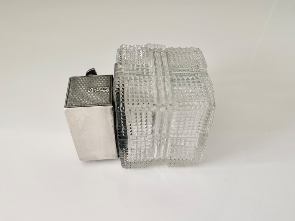 A square geometric cut glass travelling inkwell with a hallmarked sterling silver hinged lockdown mechanism attached alongside. View VI