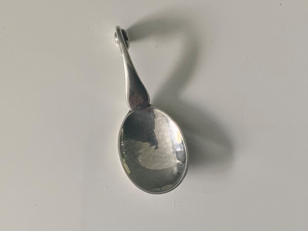 A Georg Jensen sterling silver open salt cellar with a curved handle and small spherical feet, containing a matching silver salt spoon. View III