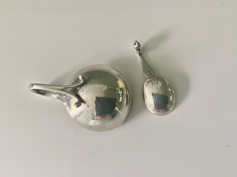 A Georg Jensen sterling silver open salt cellar with a curved handle and small spherical feet, containing a matching silver salt spoon. View IV
