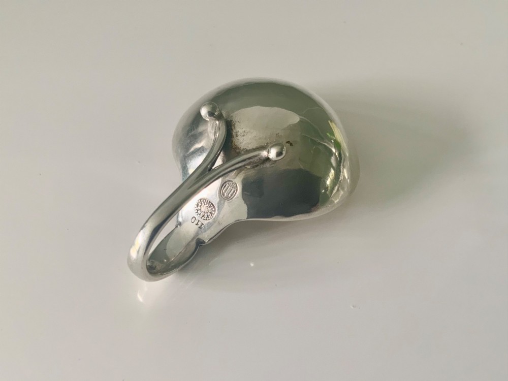 A Georg Jensen sterling silver open salt cellar with a curved handle and small spherical feet, containing a matching silver salt spoon. View V