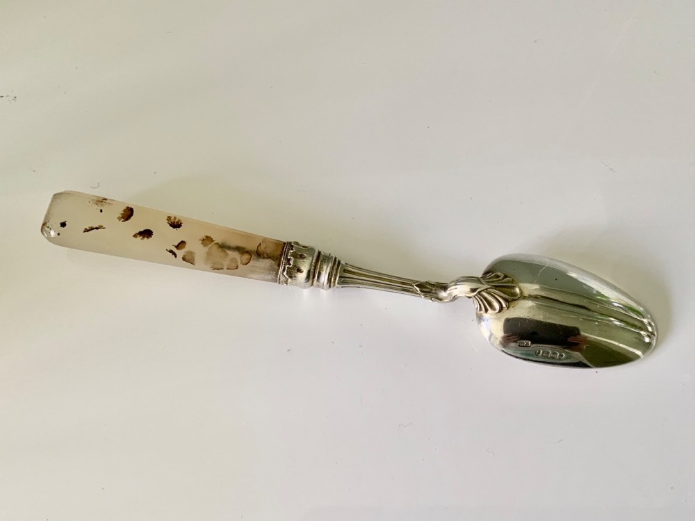 An antique silver spoon featuring an oval polished bowl, a decorative bifurcate stem, and a tapered grey agate handle. View II