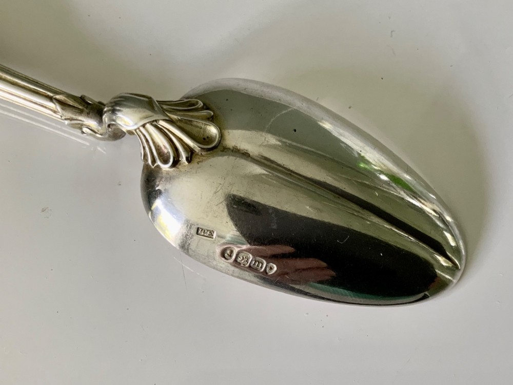 An antique silver spoon featuring an oval polished bowl, a decorative bifurcate stem, and a tapered grey agate handle. View V