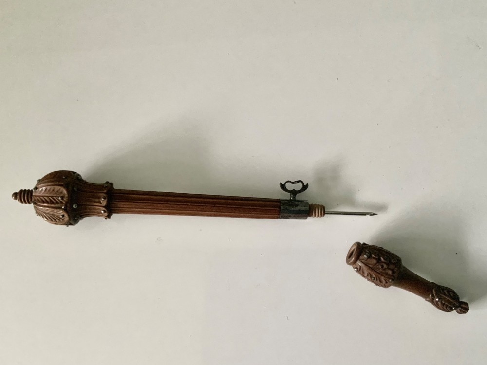 A carved wooden tambour needle handle featuring ribbed fluting, leaf motifs, cut steel stud ornamentation, and a metal thumbscrew. View V