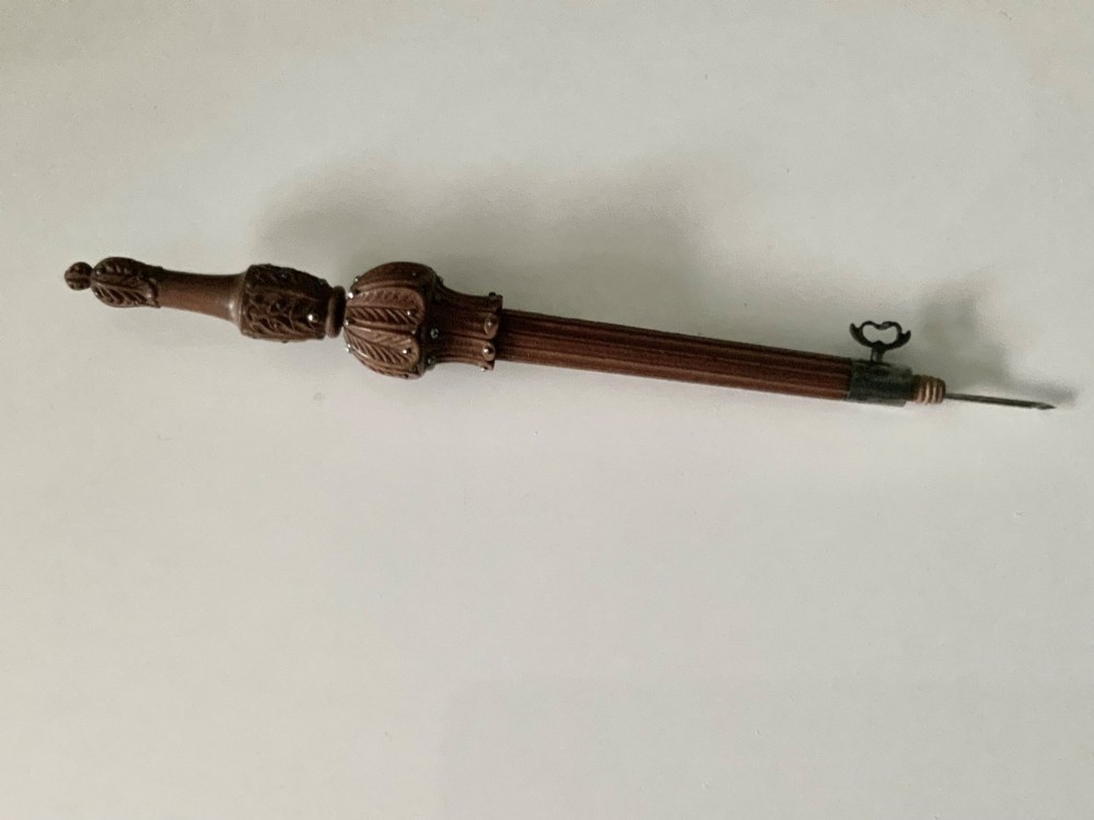 A carved wooden tambour needle handle featuring ribbed fluting, leaf motifs, cut steel stud ornamentation, and a metal thumbscrew. View VI