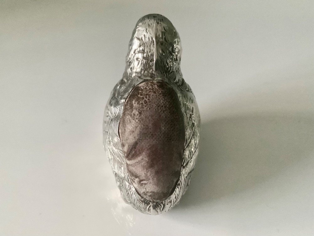 An antique sterling silver pin cushion cast in the shape of a chick with chased feather detail and a brown velvet inset cushion. View III