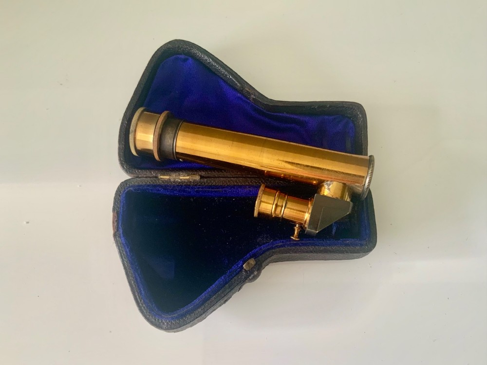 A nineteenth-century engraved brass pocket spectroscope resting inside an open fitted black leather case lined with bright blue velvet. View II