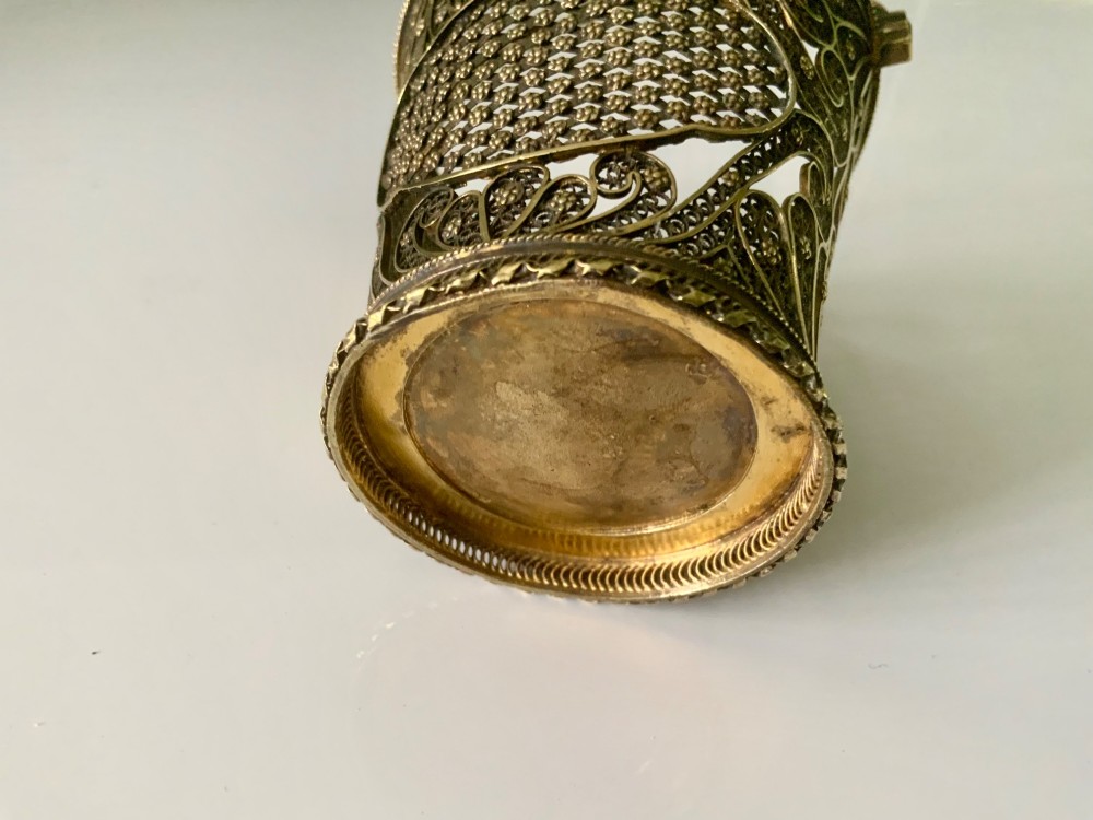 A small cylindrical silver gilt filigree basket with a twisted swing handle and intricate openwork lacelike patterns. View III