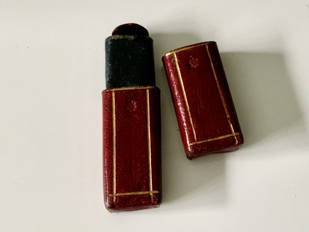 An antique folding veterinary lancet with tortoiseshell handles and a short steel blade alongside a red gilt-tooled leather case. View IV