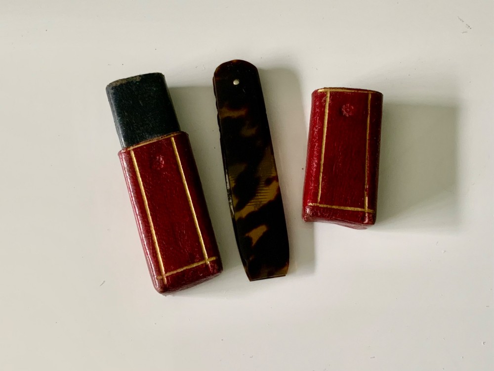 An antique folding veterinary lancet with tortoiseshell handles and a short steel blade alongside a red gilt-tooled leather case. View V