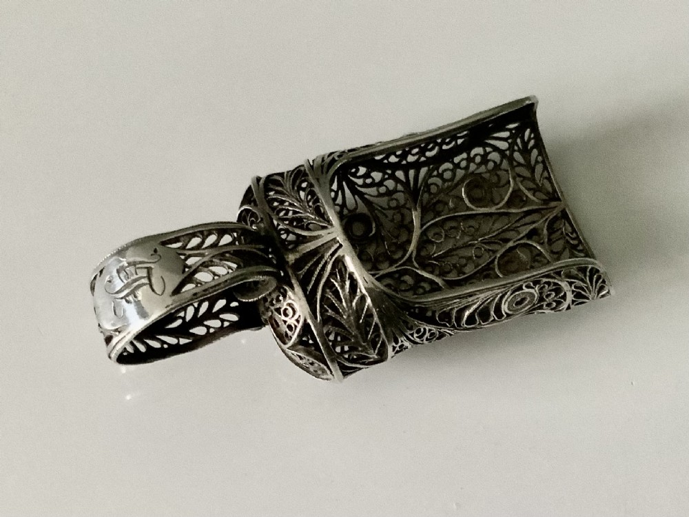 An antique Georgian silver filigree tea caddy spoon featuring intricate openwork scroll patterns and an engraved monogram cartouche on the loop handle.