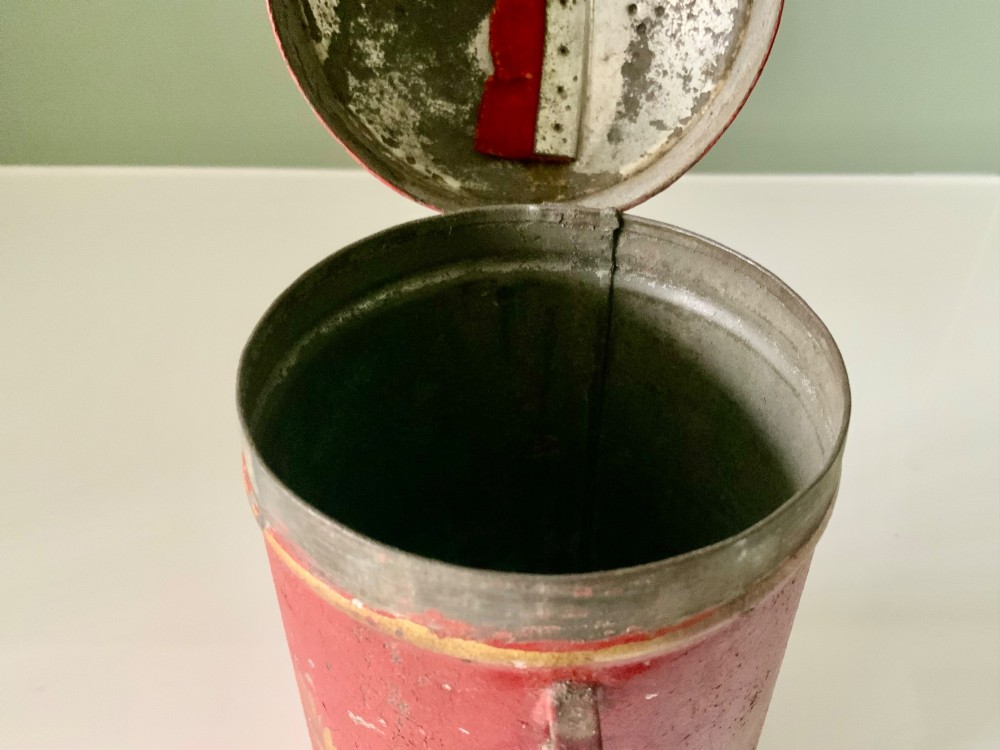 A cylindrical red painted toleware money box dated 1818 featuring a domed top with coin slot, metal latch, and gilded leaf decoration. View VIII