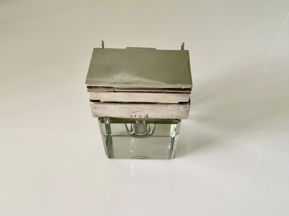 A square clear glass inkwell featuring a hallmarked sterling silver hinged lid, integrated stamp compartment, and side pen rests. View IV