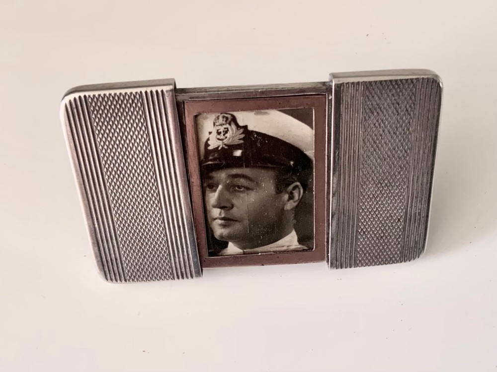 An Art Deco silver travelling photograph frame with engine-turned geometric patterns on the sliding outer panels, displaying a black and white portrait.