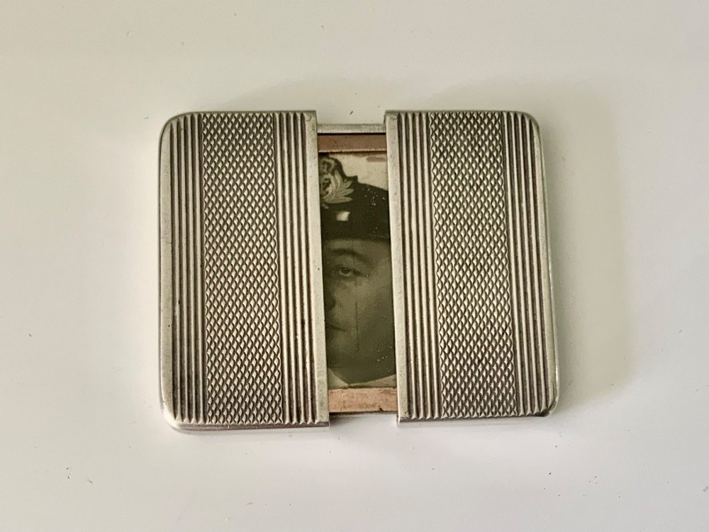 An Art Deco silver travelling photograph frame with engine-turned geometric patterns on the sliding outer panels, displaying a black and white portrait. View IV
