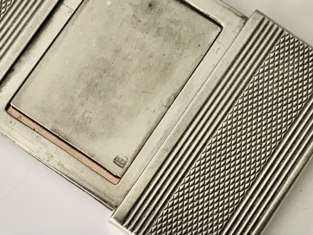 An Art Deco silver travelling photograph frame with engine-turned geometric patterns on the sliding outer panels, displaying a black and white portrait. View VI