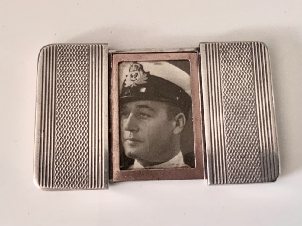 An Art Deco silver travelling photograph frame with engine-turned geometric patterns on the sliding outer panels, displaying a black and white portrait. View VII