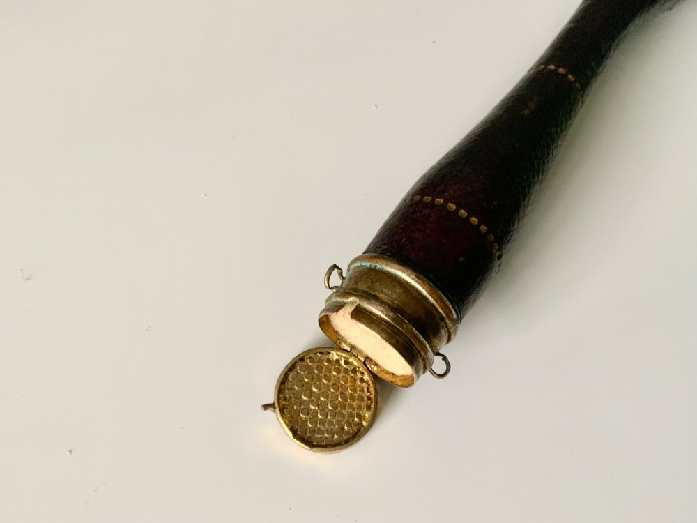 A 19th-century French hand fan featuring a dark brown leather handle with an integrated gilt metal vinaigrette grille at the base and a pleated purple leaf. View III