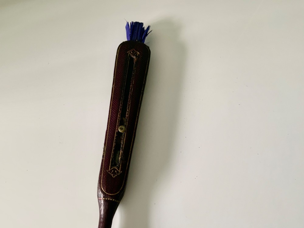 A 19th-century French hand fan featuring a dark brown leather handle with an integrated gilt metal vinaigrette grille at the base and a pleated purple leaf. View IV