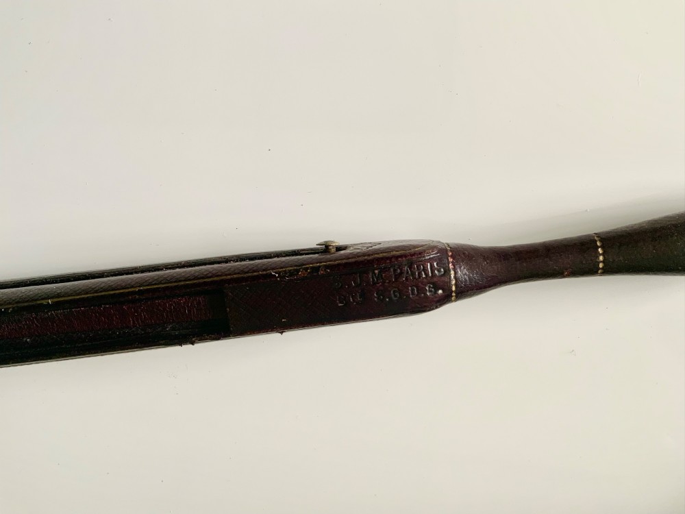 A 19th-century French hand fan featuring a dark brown leather handle with an integrated gilt metal vinaigrette grille at the base and a pleated purple leaf. View V