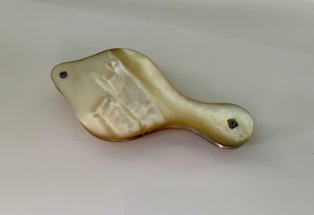 A Georgian folding pocket magnifying glass encased in iridescent cream mother of pearl plates with silver rivets.