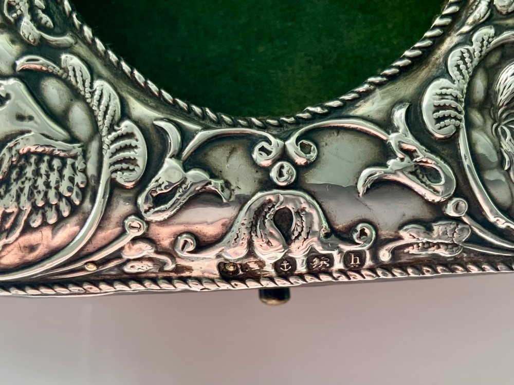 An embossed silver pocket watch stand featuring the Reynolds Angels cherub motif with a circular opening and velvet lining. View II