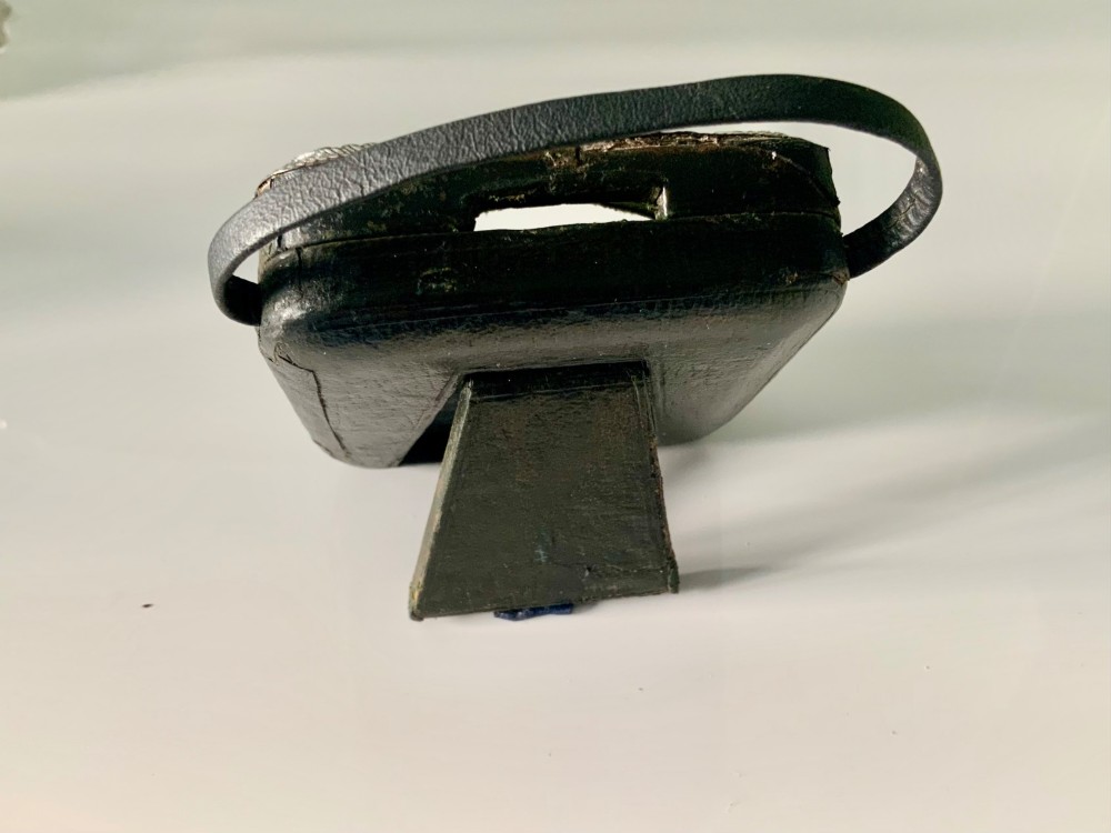 An embossed silver pocket watch stand featuring the Reynolds Angels cherub motif with a circular opening and velvet lining. View V