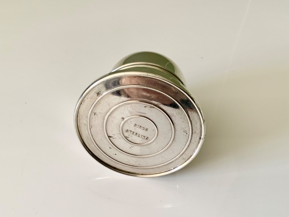 A domed sterling silver ring box resting on a stepped circular base with an embossed logo on top. View II