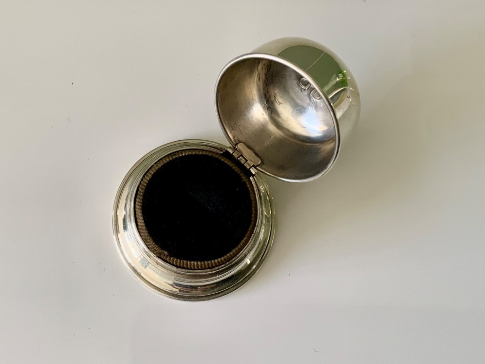 A domed sterling silver ring box resting on a stepped circular base with an embossed logo on top. View IV