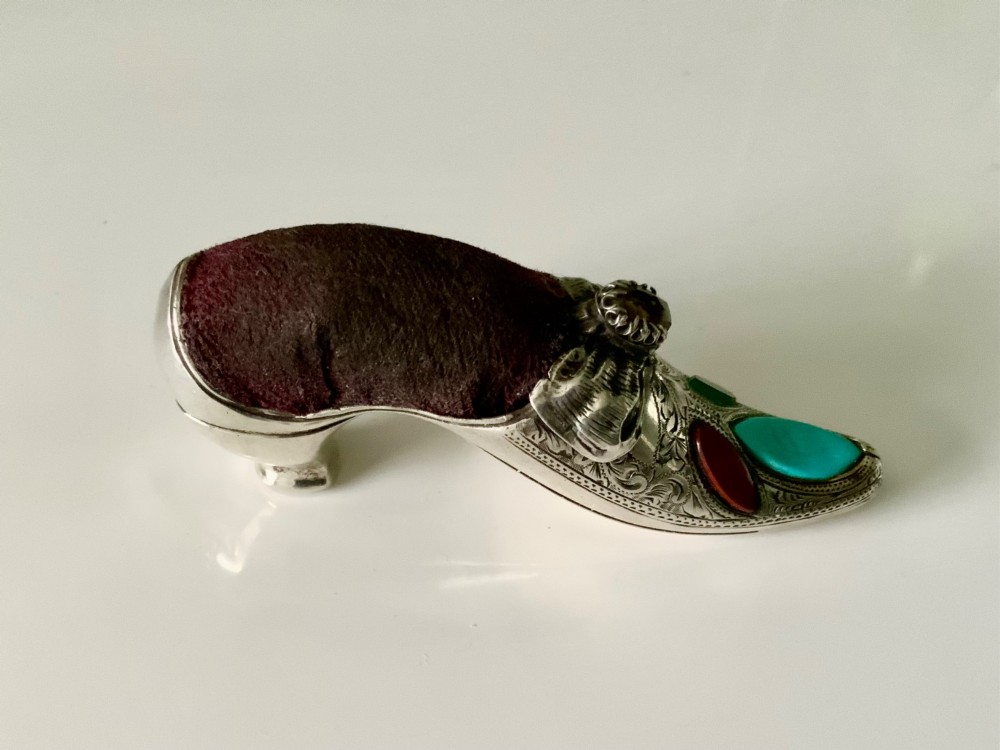 A Victorian silver shoe-shaped pin cushion embellished with hand engraving, set agate stones, and a dark velvet cushion top. View IV