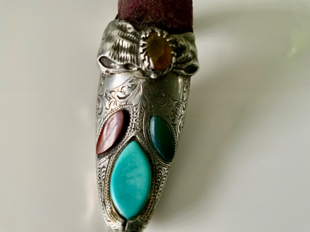 A Victorian silver shoe-shaped pin cushion embellished with hand engraving, set agate stones, and a dark velvet cushion top. View V
