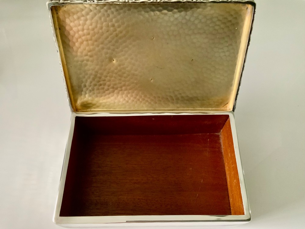A rectangular silver plated box featuring a hand-hammered lid and a dark oval central inset framed by decorative detailing. View III