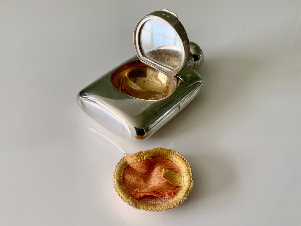 A hallmarked sterling silver combination scent bottle and powder compact with a hinged lid revealing an inner well alongside a small fabric powder puff. View II