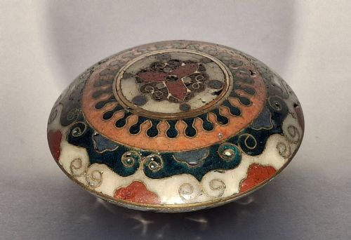 fig 1. A circular Japanese manju netsuke in polychrome cloisonne enamel with central floral medallion and spiral border patterns.