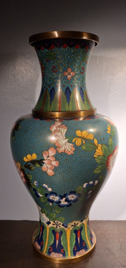 fig 2. A large Chinese cloisonne enamel vase with pink and yellow floral motifs over a blue geometric ground and brass rim.