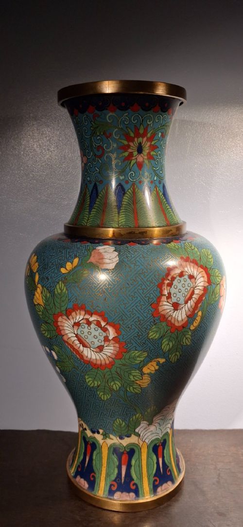 fig 1. A large Chinese cloisonne enamel vase with pink and yellow floral motifs over a blue geometric ground and brass rim.